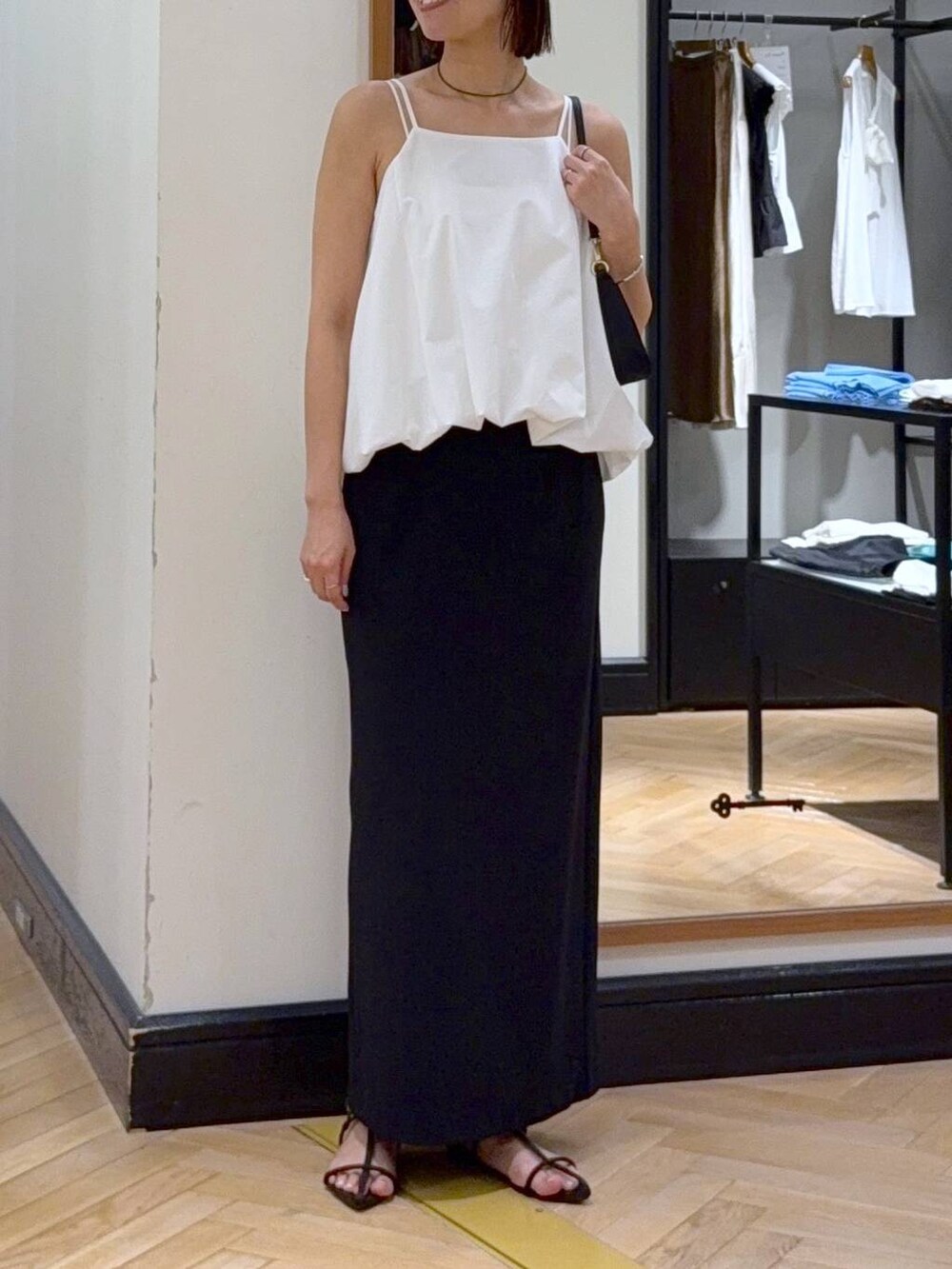 ブラウン系のサンダル、ホワイト系のセットアップ、ブラック系のショルダーバッグを着用したレディースの夏コーディネートの2枚目の写真