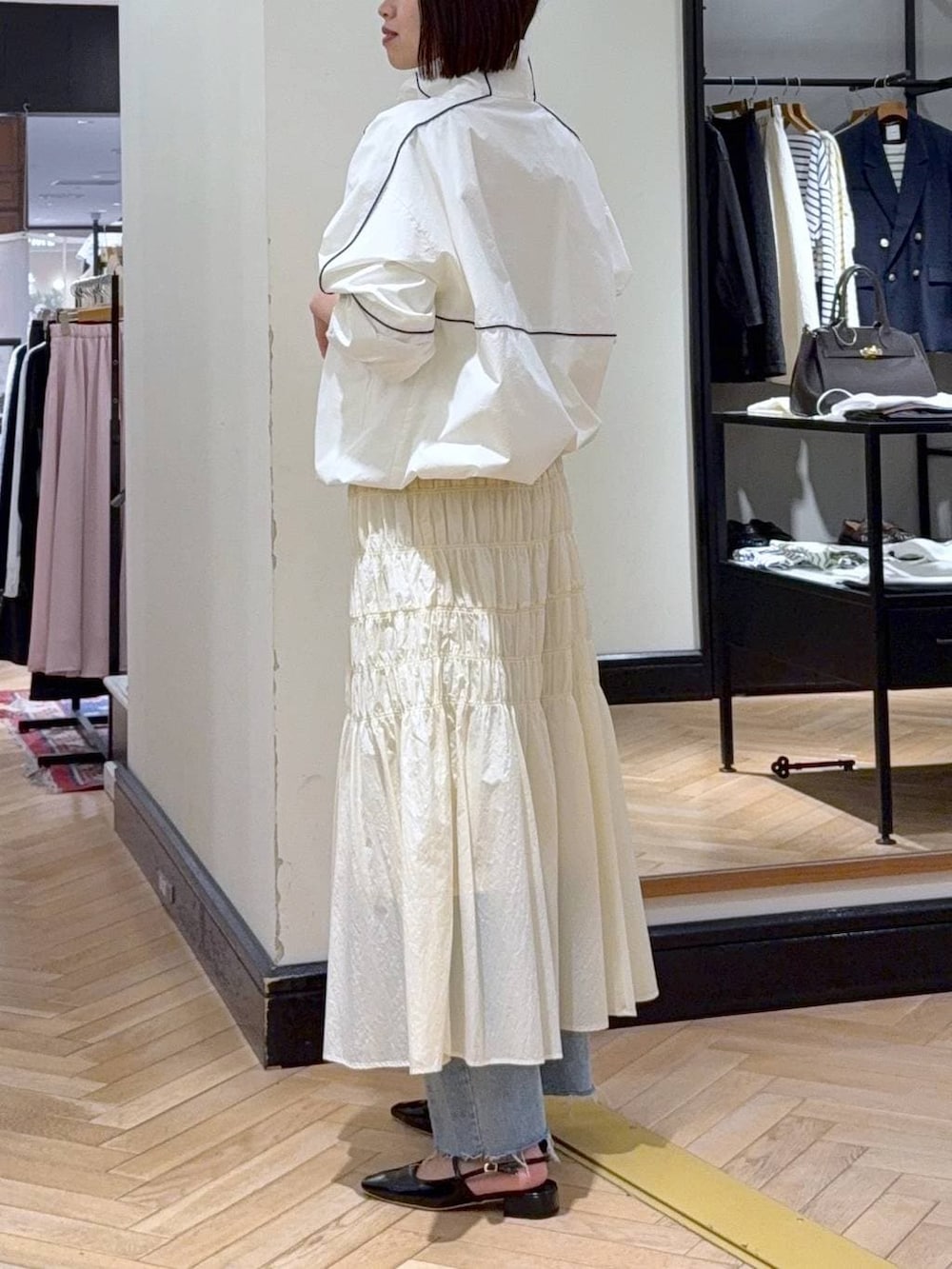 ブラック系のショルダーバッグ、ブルー系のデニムパンツ、ホワイト系のブルゾンを着用したレディースの冬コーディネートの3枚目の写真