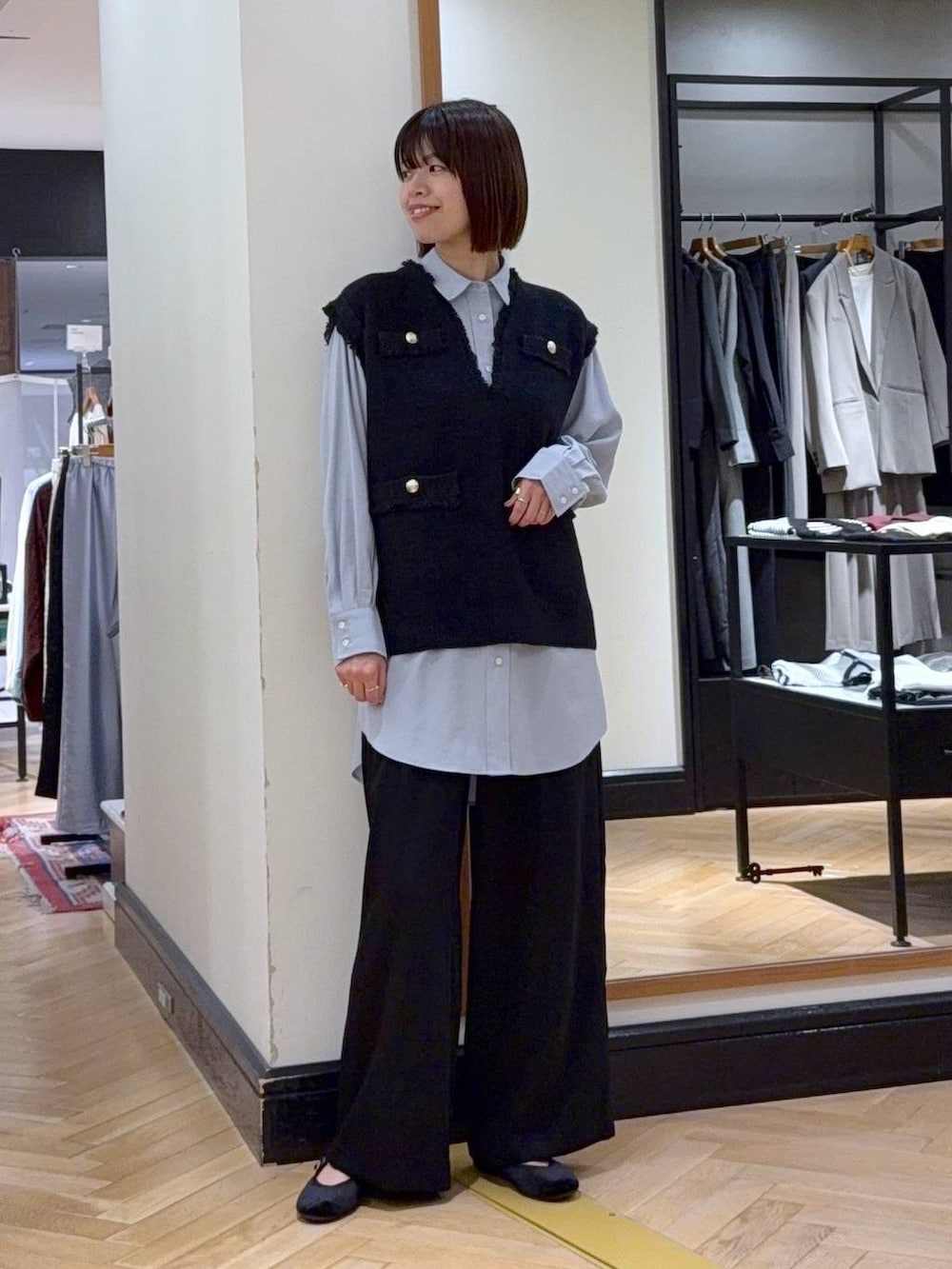 グレー系のベスト、ブラック系のスラックス、ブラック系のバレエシューズを着用したレディースの秋コーディネートの5枚目の写真