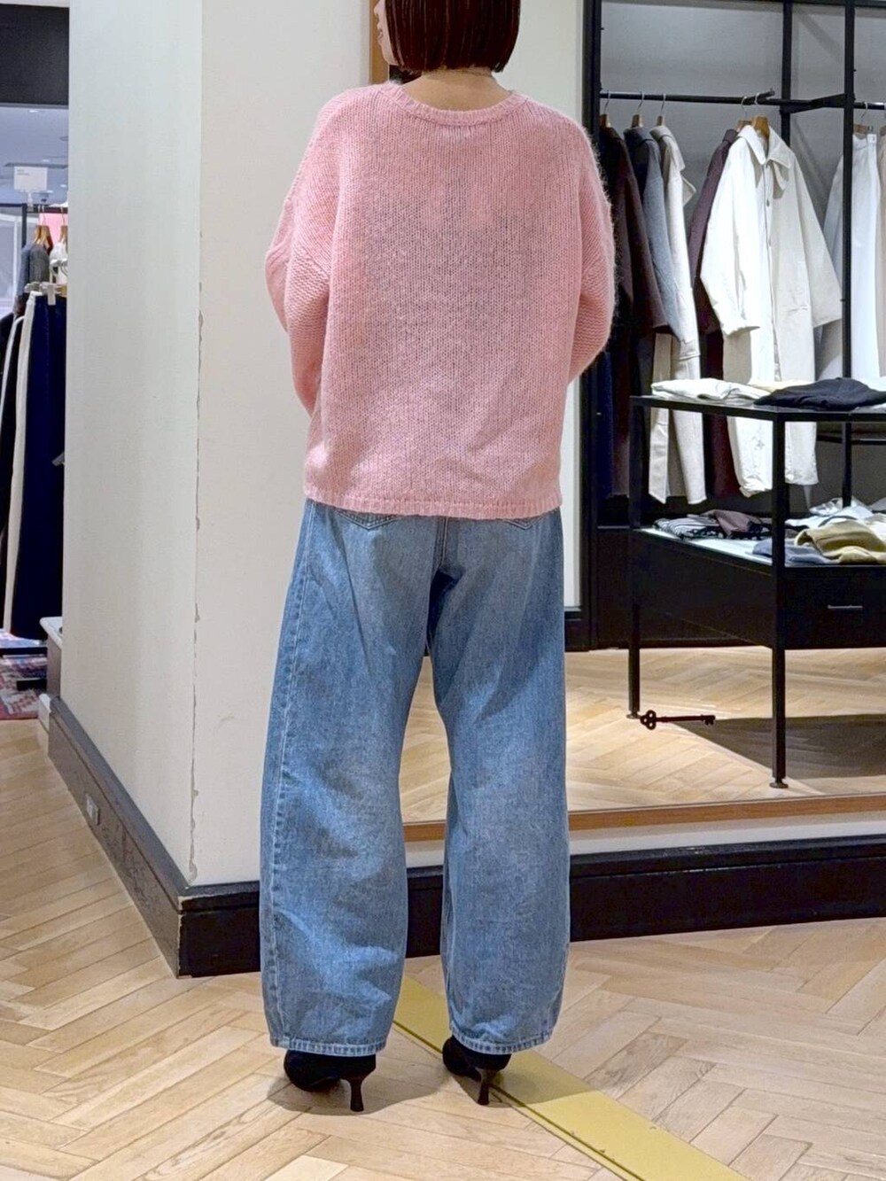 ブルー系のデニムパンツ、ブラック系のショルダーバッグ、ブラック系のブーツを着用したレディースの秋コーディネートの4枚目の写真