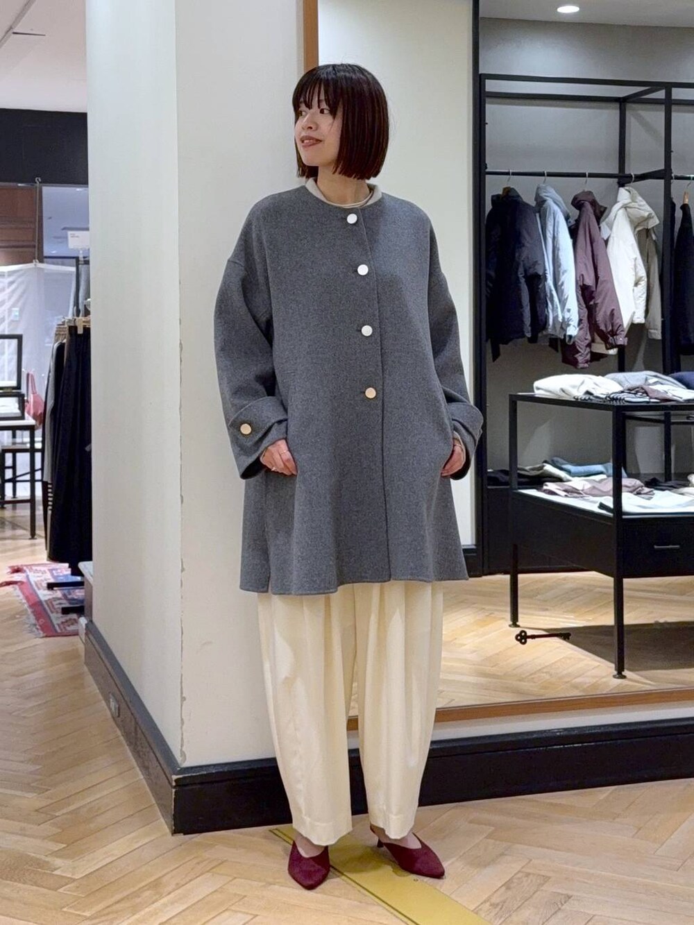 ホワイト系のスラックス、レッド系のパンプス、ブラック系のショルダーバッグを着用したレディースの秋コーディネートの2枚目の写真