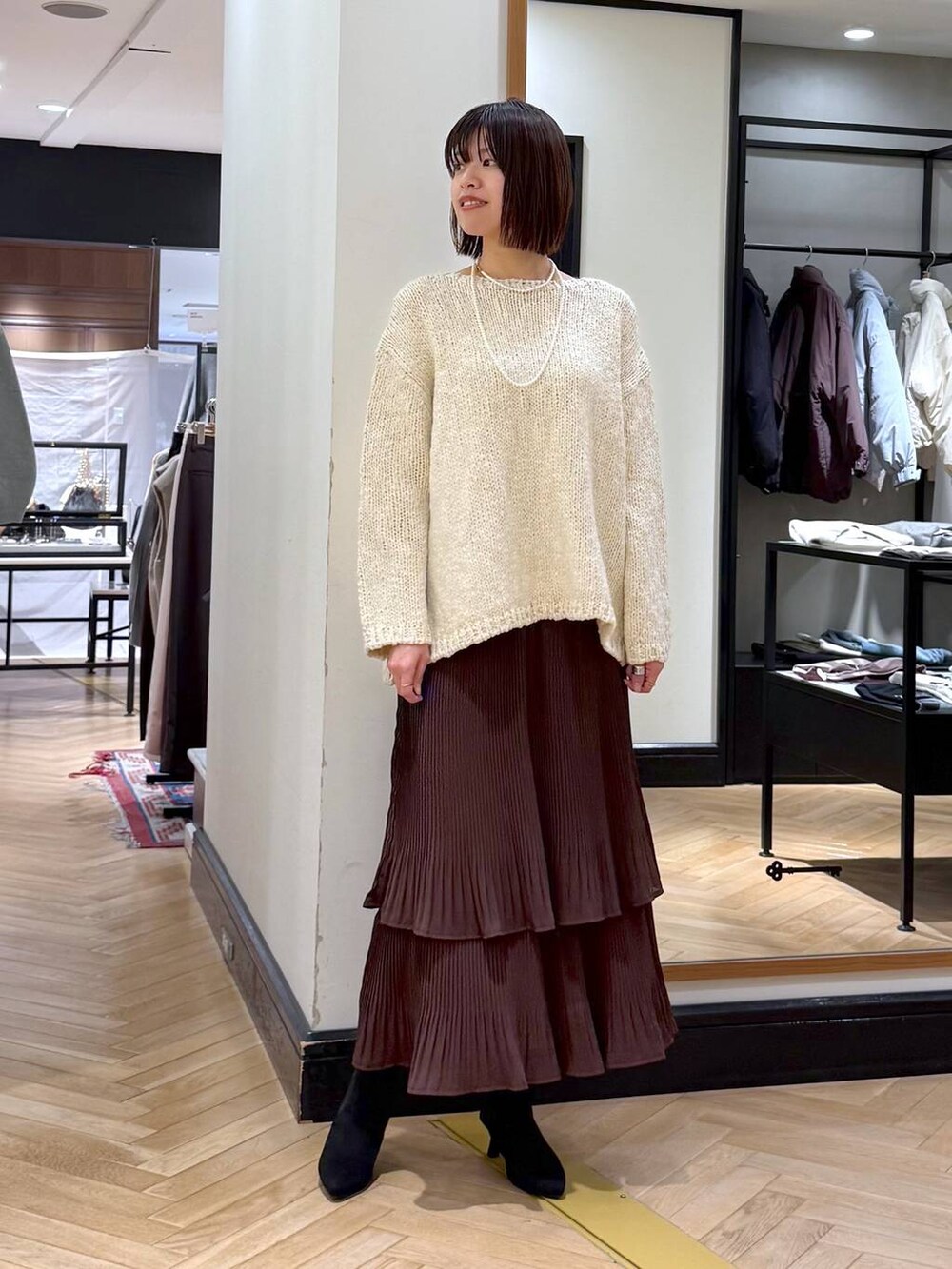 ブラウン系のスカート、ブラック系のショルダーバッグ、ブラック系のブーツを着用したレディースの秋コーディネートの5枚目の写真