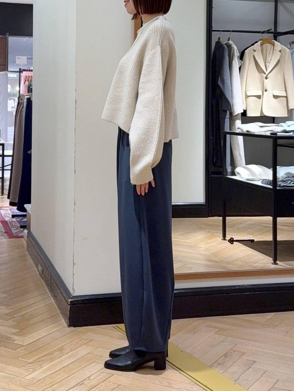 ブラック系のブーツ、ホワイト系のニット/セーター、ブラウン系のハンドバッグを着用したレディースの冬コーディネートの2枚目の写真