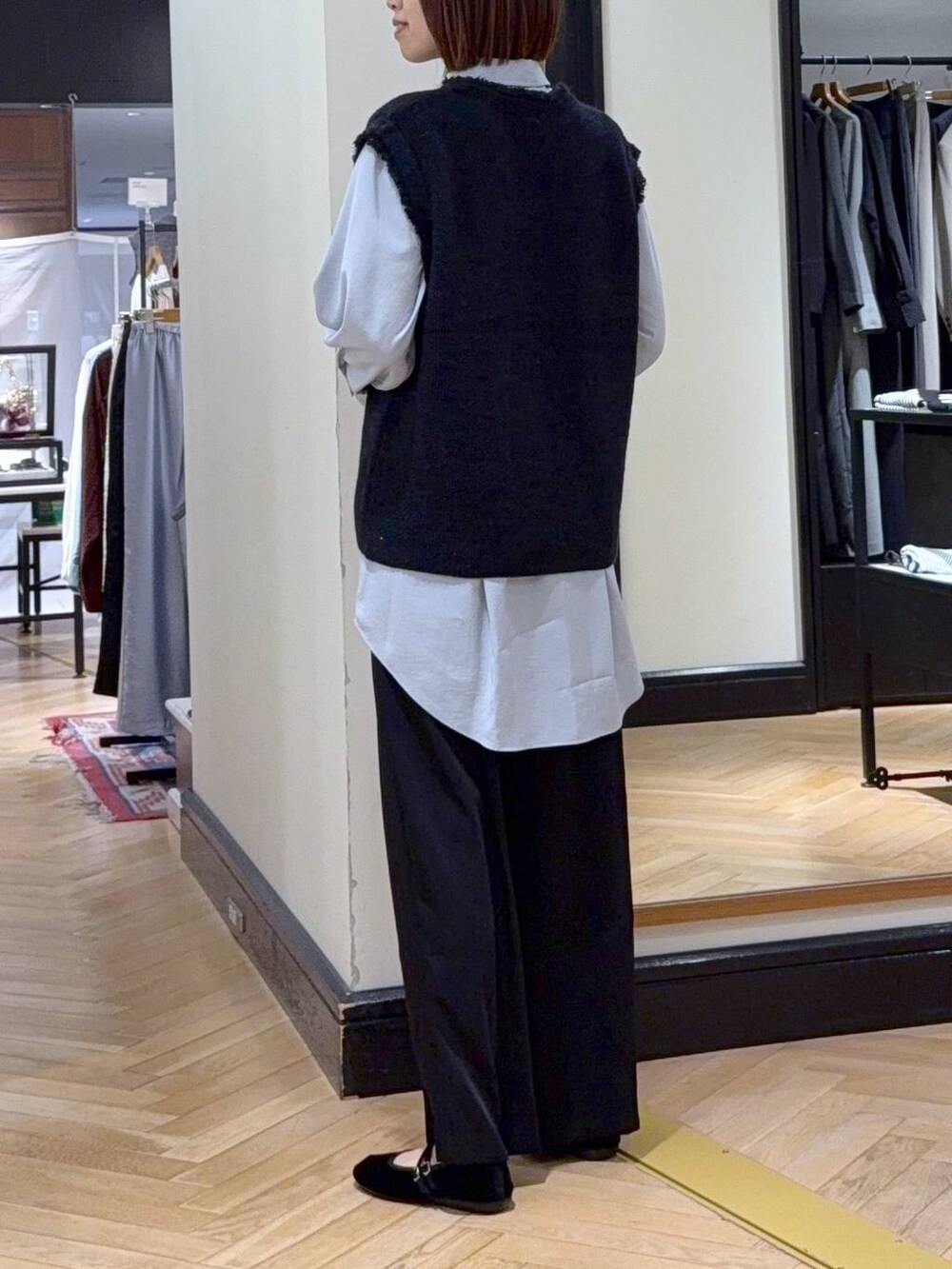 グレー系のベスト、ブラック系のスラックス、ブラック系のバレエシューズを着用したレディースの秋コーディネートの4枚目の写真