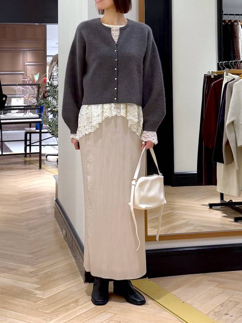 ホワイト系のショルダーバッグ、ベージュ系のTシャツ/カットソー、ホワイト系のスカートを着用したレディースの秋コーディネートの2枚目の写真