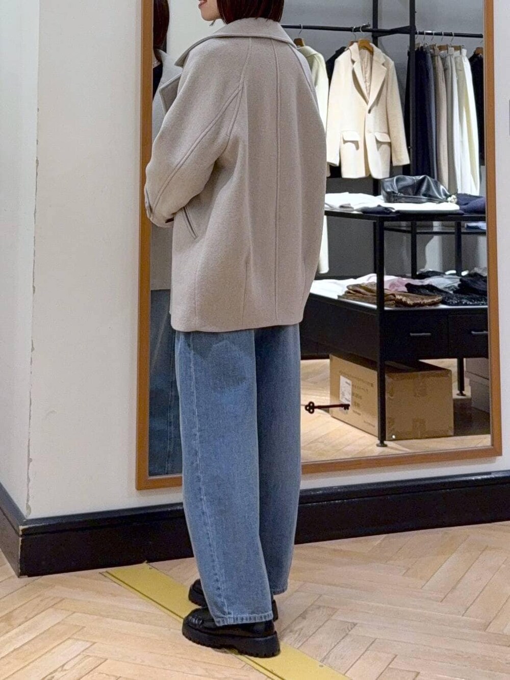 ベージュ系のピーコート、ブルー系のデニムパンツ、ブラック系のカーディガン/ボレロを着用したレディースの冬コーディネートの3枚目の写真