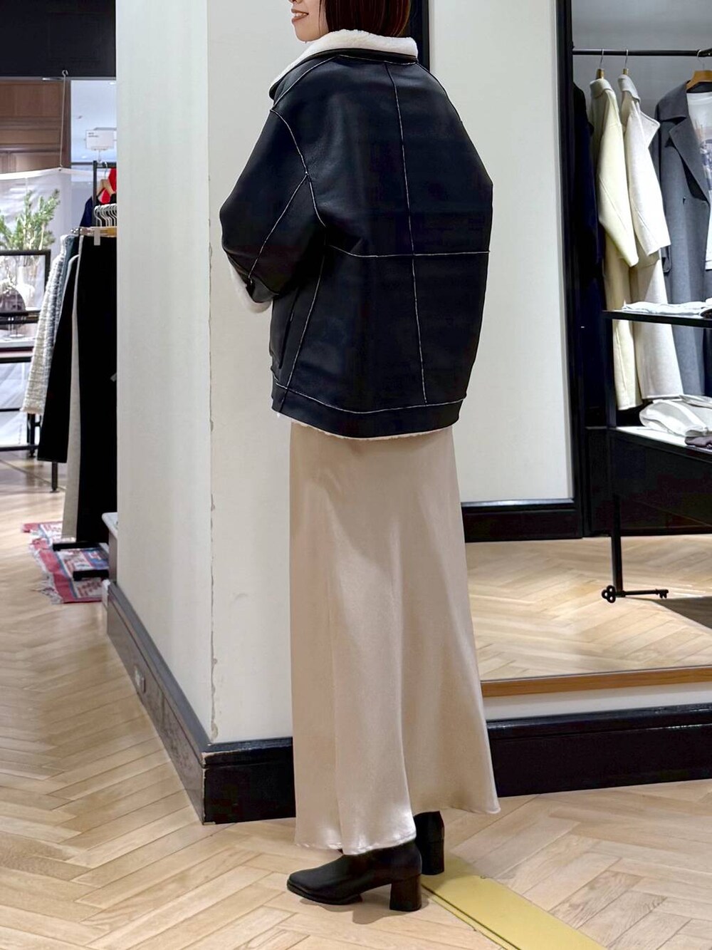 ブラック系のブーツ、ベージュ系のスカート、ブラック系のその他アウターを着用したレディースの冬コーディネートの5枚目の写真