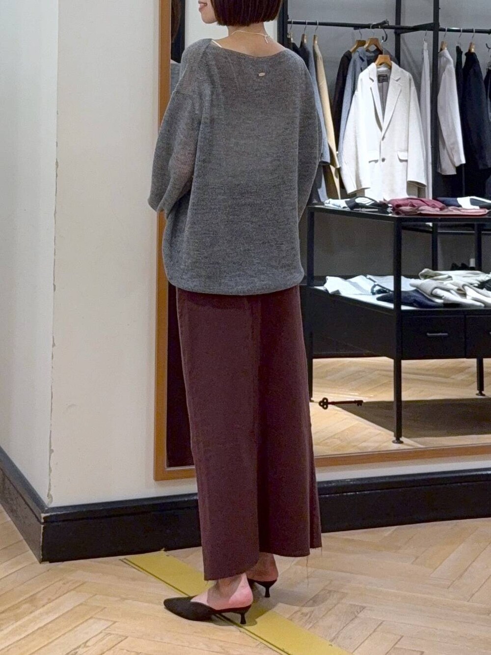 グレー系のニット/セーター、レッド系のデニムスカート、ブラウン系のパンプスを着用したレディースの秋コーディネートの3枚目の写真