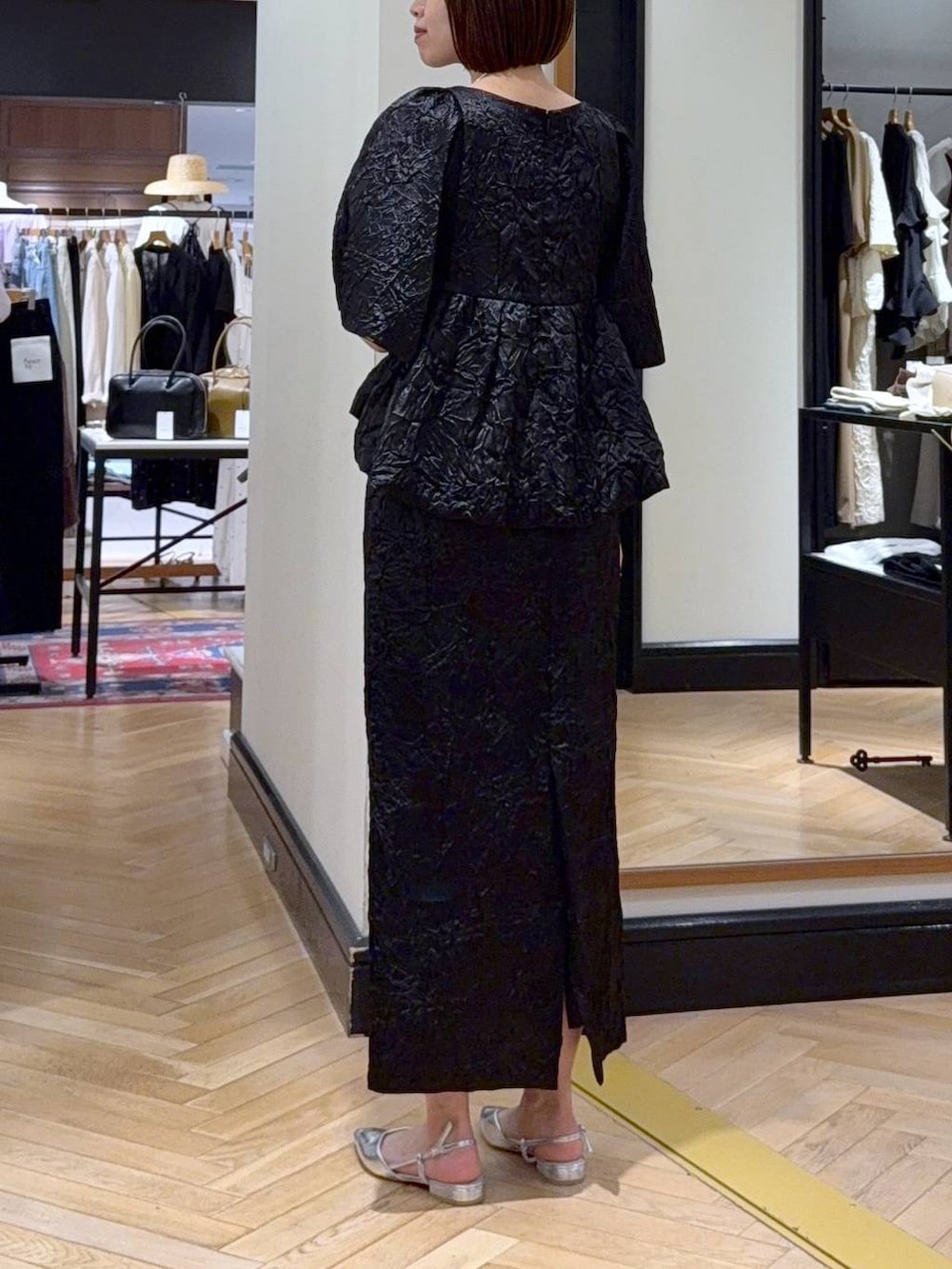 ホワイト系のハンドバッグ、シルバー系のパンプス、ブラック系のワンピースを着用したレディースの夏コーディネートの3枚目の写真