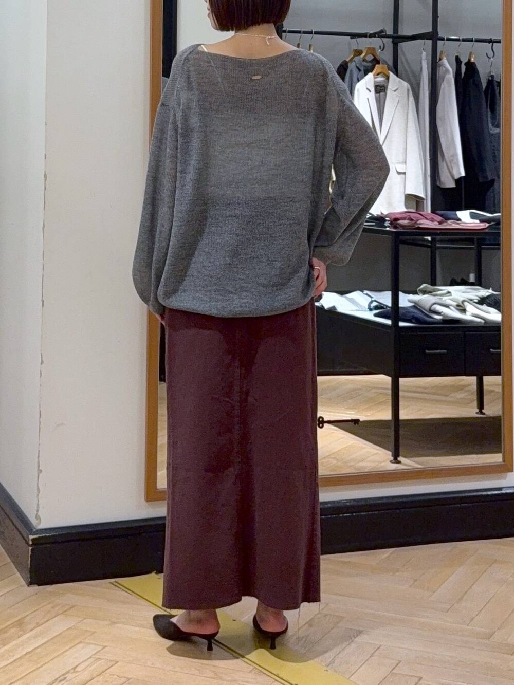 グレー系のニット/セーター、レッド系のデニムスカート、ブラウン系のパンプスを着用したレディースの秋コーディネートの4枚目の写真