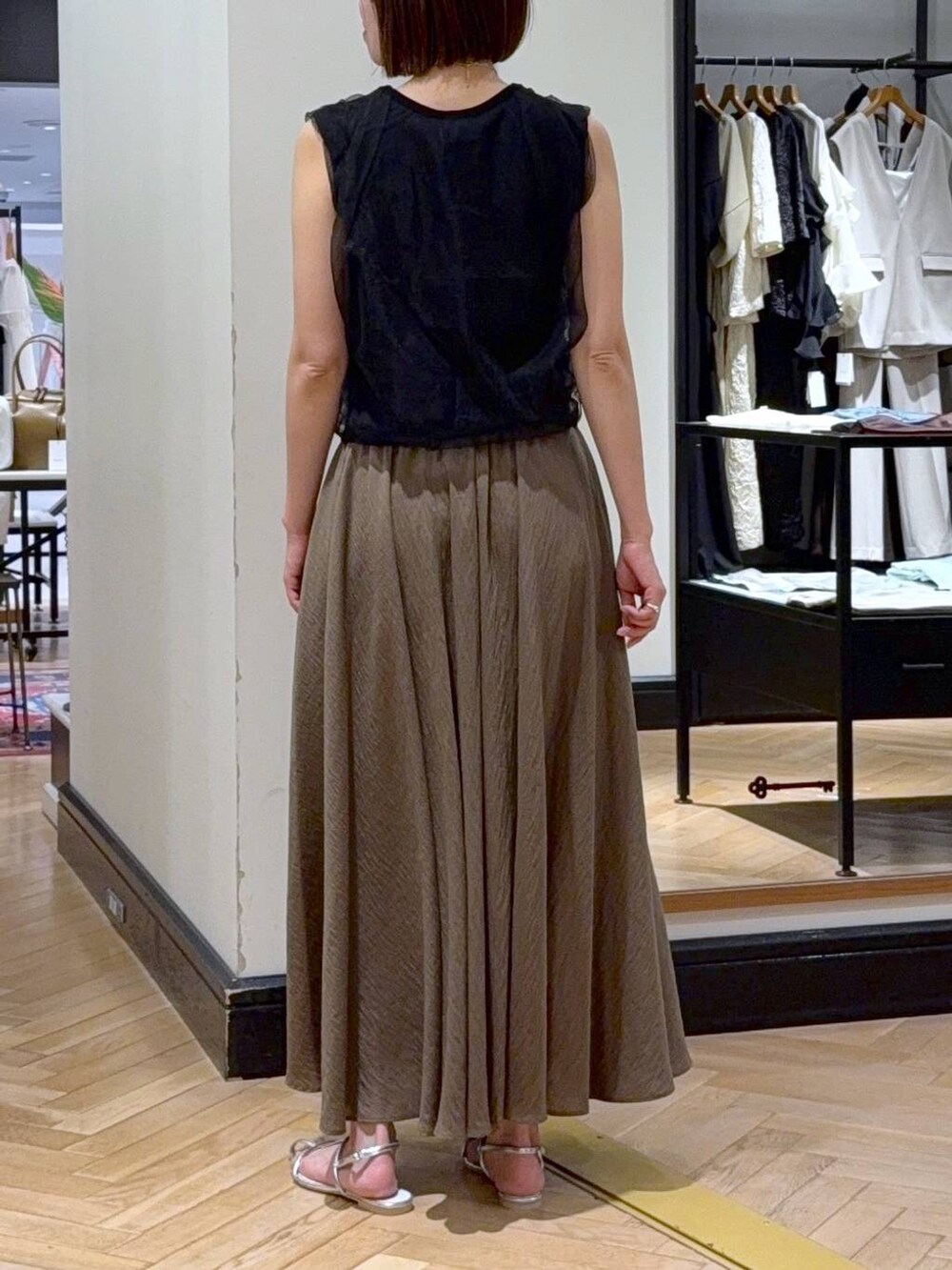 シルバー系のサンダル、ブラック系のニット/セーター、グリーン系のスカートを着用したレディースの夏コーディネートの5枚目の写真