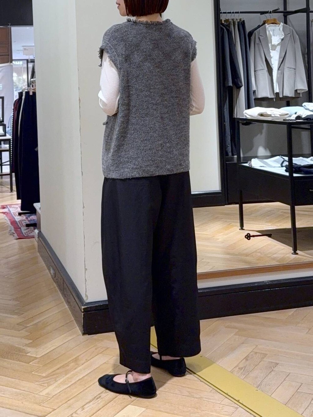 ブラック系のスラックス、グレー系のベスト、ホワイト系のTシャツ/カットソーを着用したレディースの秋コーディネートの3枚目の写真