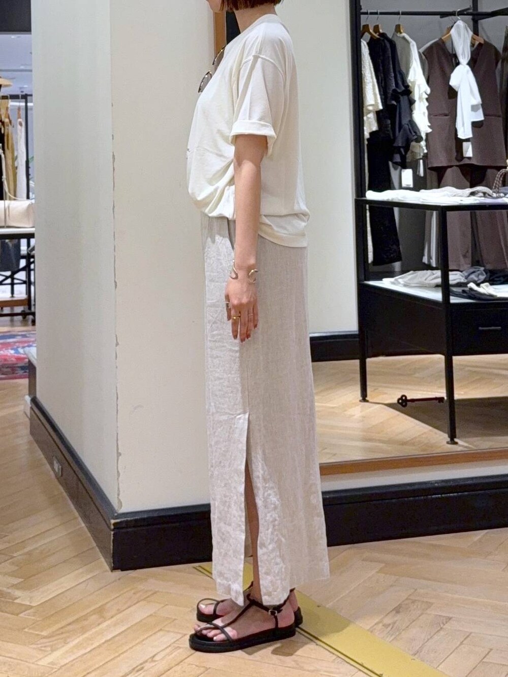 ホワイト系のショルダーバッグ、ホワイト系のTシャツ/カットソー、ブラック系のサンダルを着用したレディースの夏コーディネートの2枚目の写真