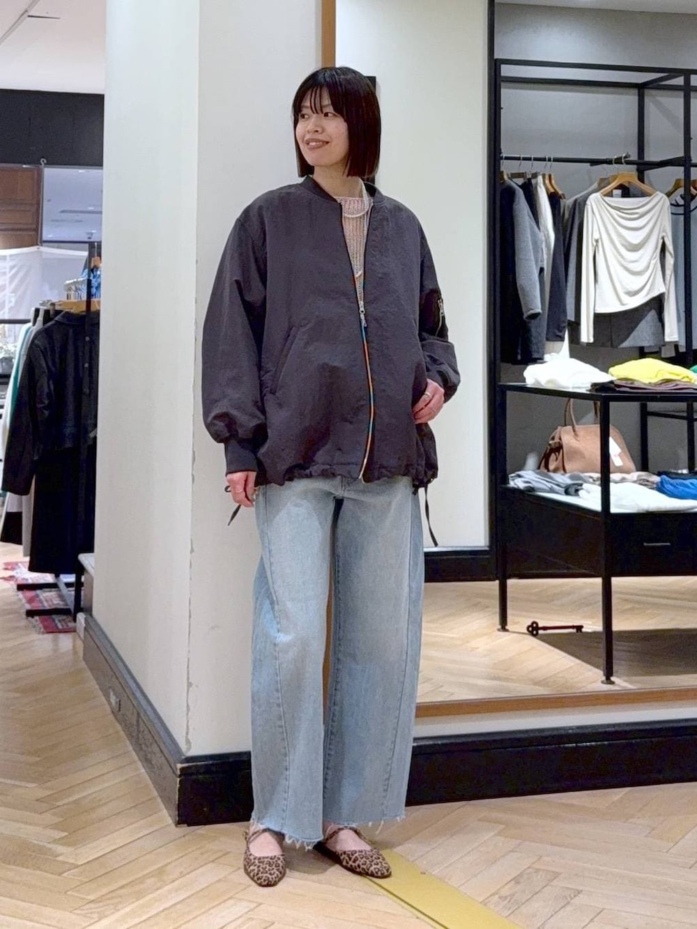 グレー系のMA-1、ブルー系のデニムパンツ、ブラック系のショルダーバッグを着用したレディースの春コーディネートの2枚目の写真