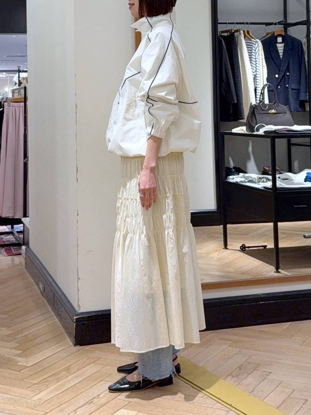 ブラック系のショルダーバッグ、ブルー系のデニムパンツ、ホワイト系のブルゾンを着用したレディースの冬コーディネートの2枚目の写真