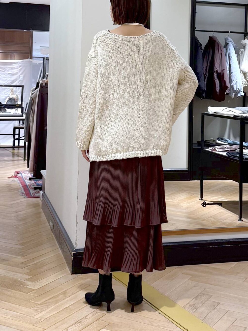 ブラウン系のスカート、ブラック系のショルダーバッグ、ブラック系のブーツを着用したレディースの秋コーディネートの4枚目の写真