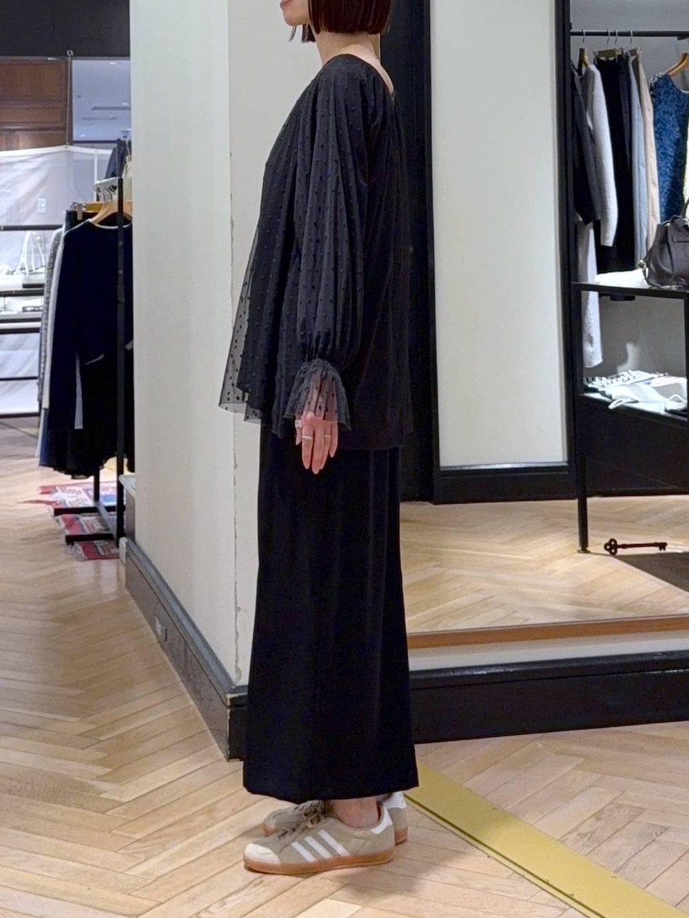 グリーン系のトートバッグ、ベージュ系のスニーカー、ブラック系のシャツ/ブラウスを着用したレディースの春コーディネートの2枚目の写真