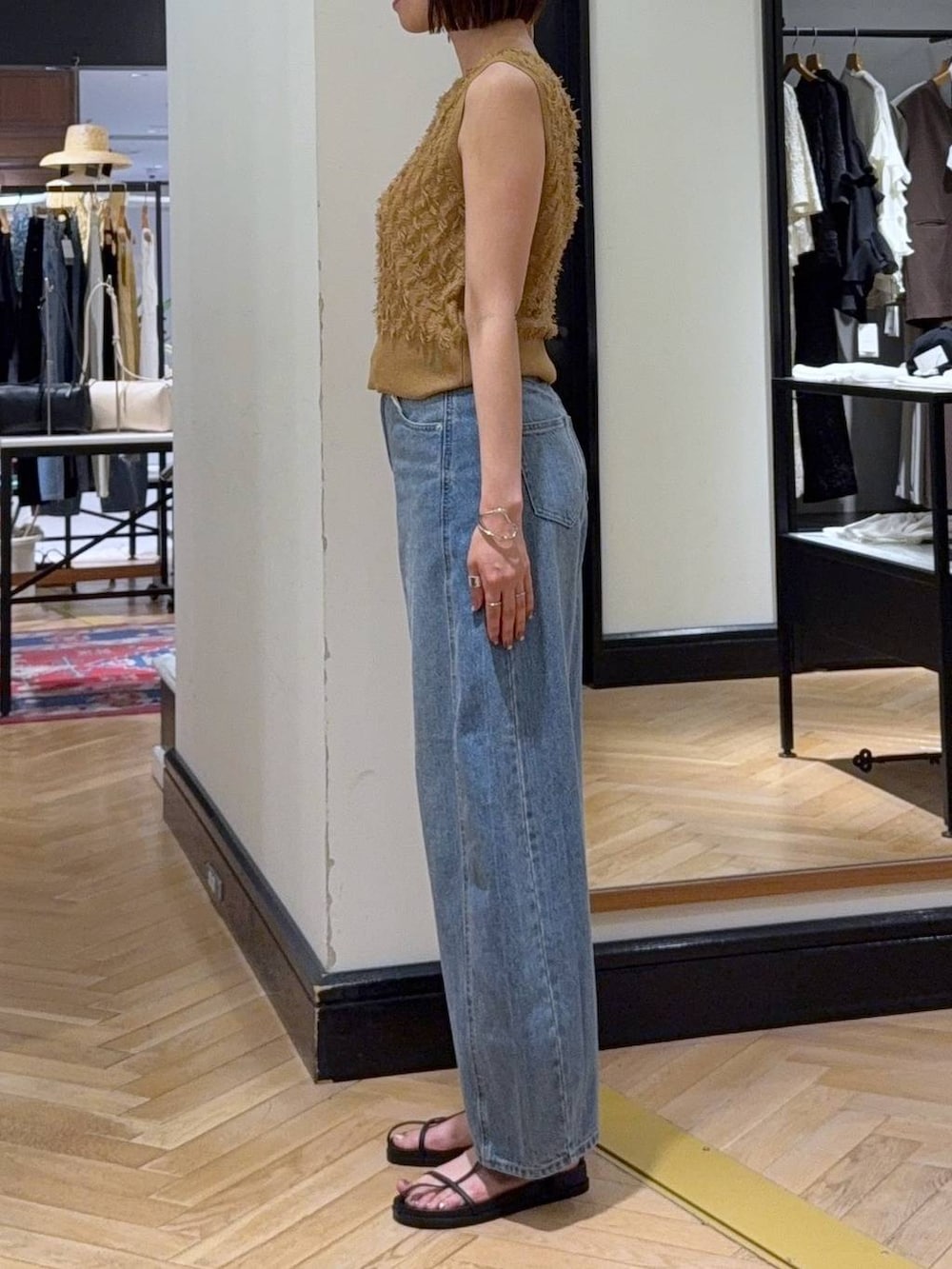 ブルー系のデニムパンツ、ホワイト系のショルダーバッグ、イエロー系のニット/セーターを着用したレディースの夏コーディネートの2枚目の写真