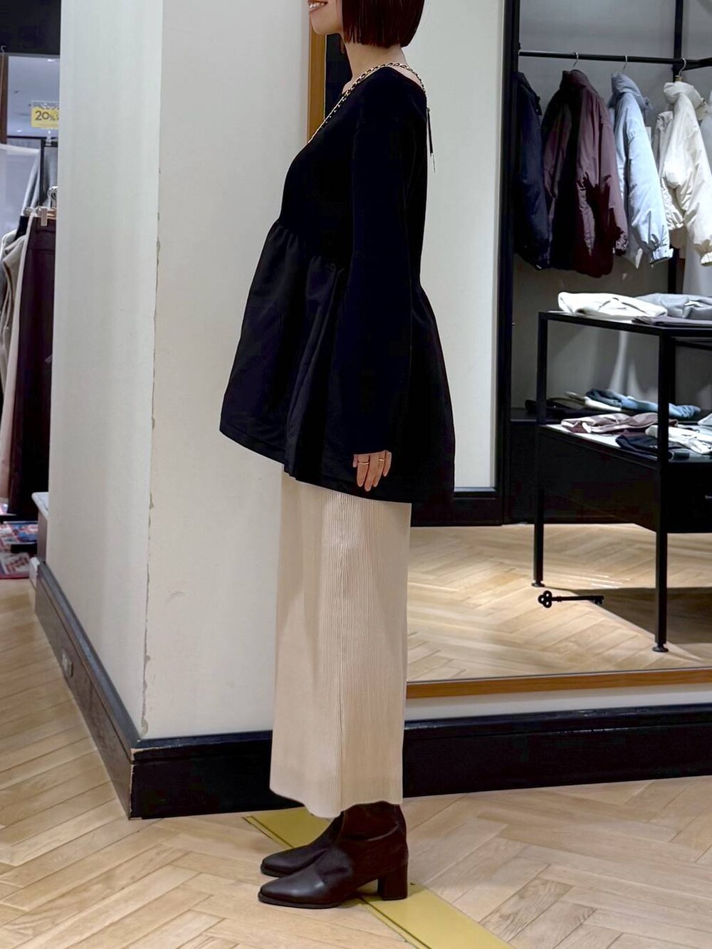 ブラウン系のブーツ、ホワイト系のスカート、ブラック系のニット/セーターを着用したレディースの秋コーディネートの2枚目の写真