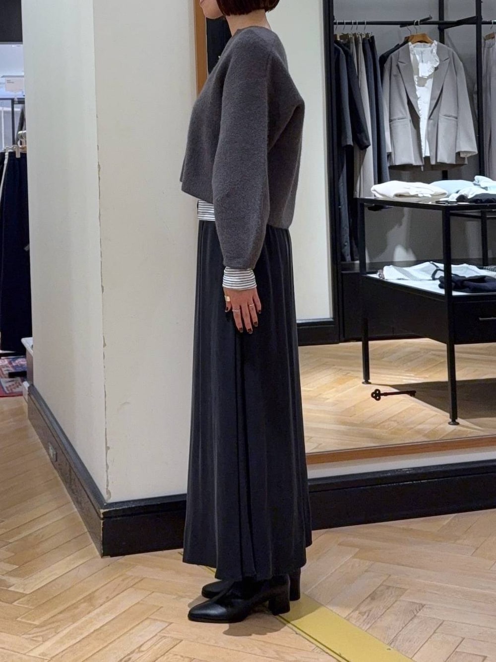 ブラック系のブーツ、グレー系のカーディガン/ボレロ、ブラック系のスカートを着用したレディースの秋コーディネートの3枚目の写真