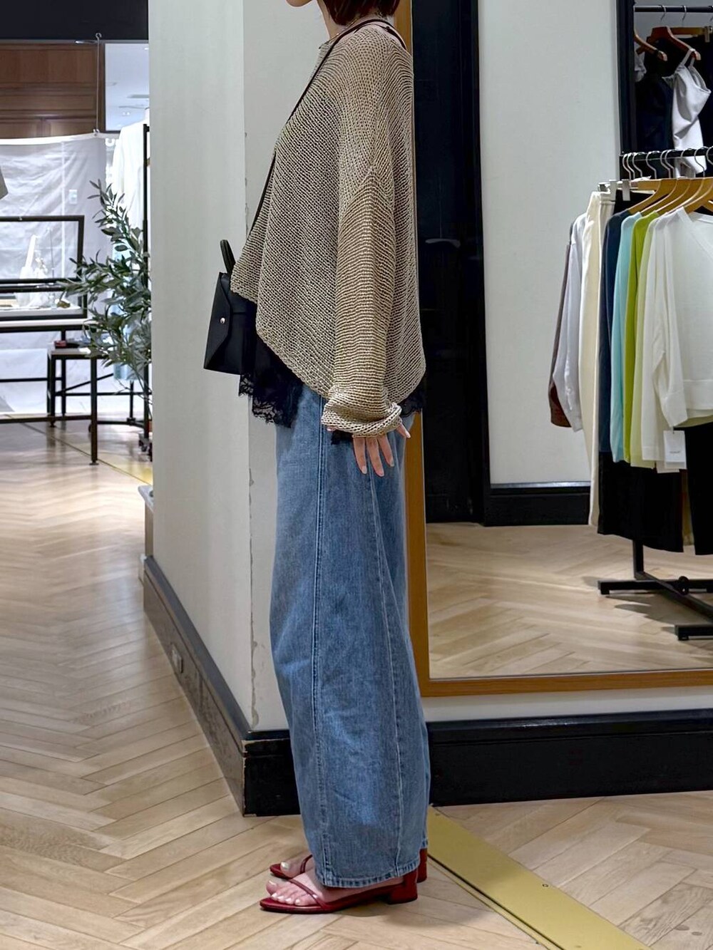 ブルー系のデニムパンツ、レッド系のサンダル、ベージュ系のニット/セーターを着用したレディースの夏コーディネートの2枚目の写真