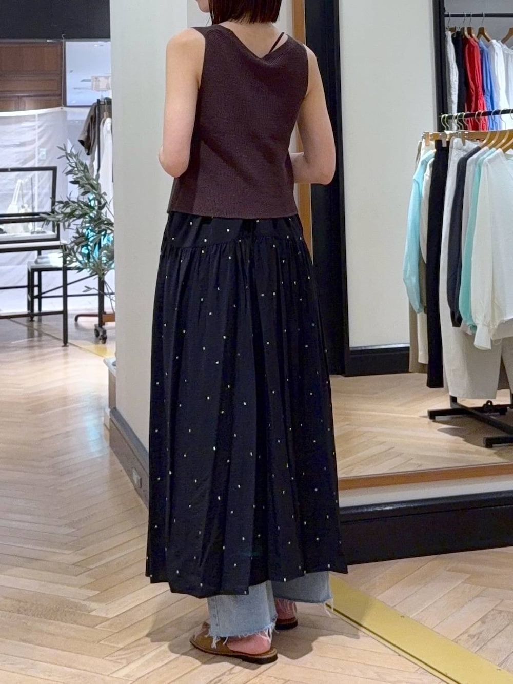 ブラック系のワンピース、ブルー系のデニムパンツ、ブラウン系のベストを着用したレディースの春コーディネートの4枚目の写真