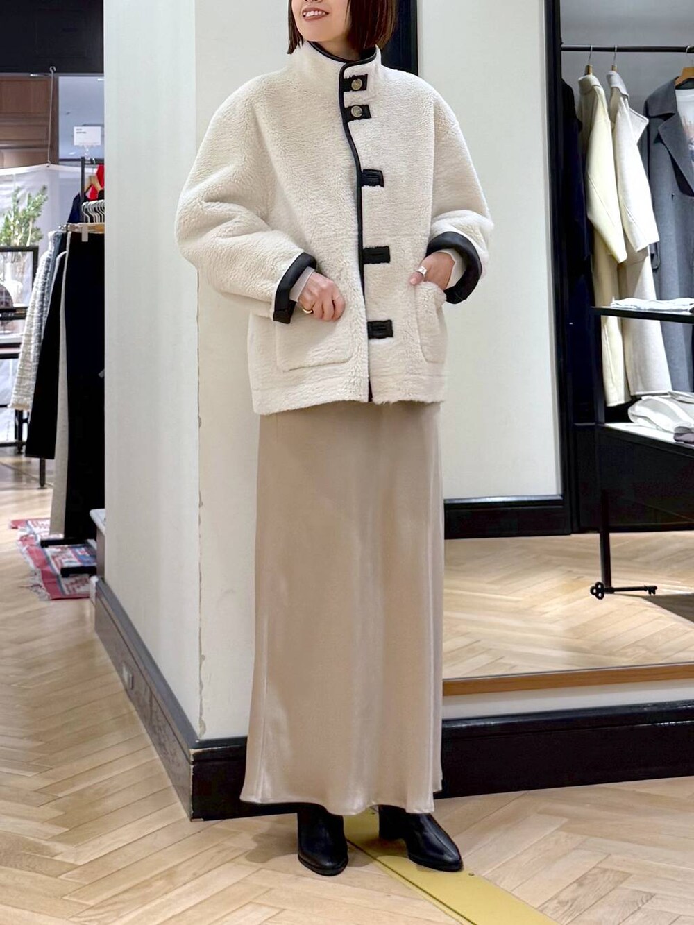 ブラック系のブーツ、ベージュ系のスカート、ブラック系のその他アウターを着用したレディースの冬コーディネートの6枚目の写真