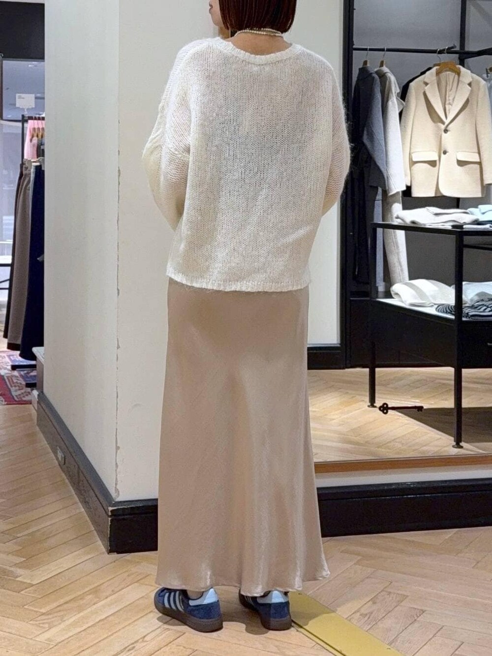 ベージュ系のスカート、ホワイト系のニット/セーター、ベージュ系のハンドバッグを着用したレディースの冬コーディネートの4枚目の写真