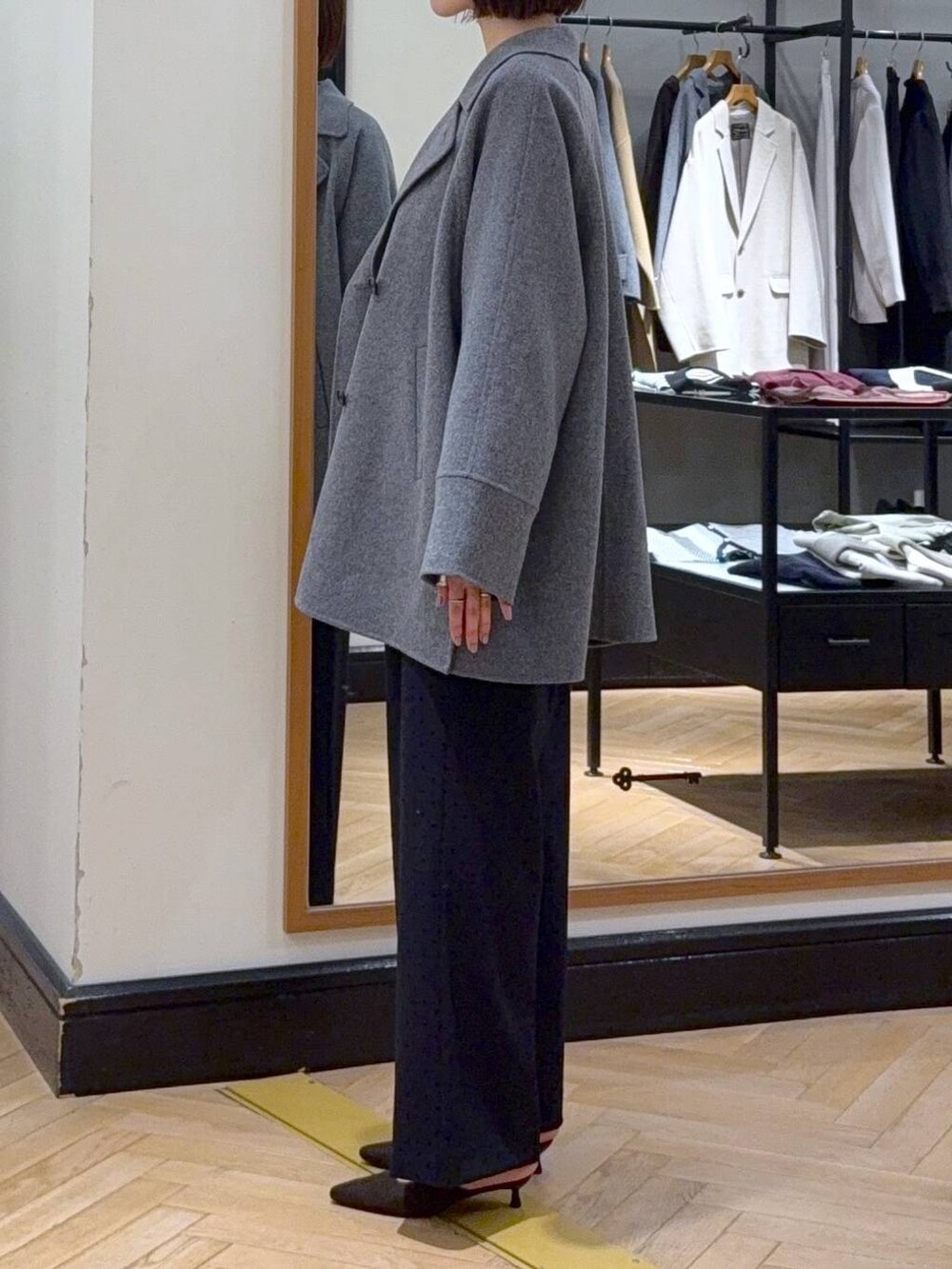 グレー系のその他アウター、ホワイト系のニット/セーター、ブラック系のスラックスを着用したレディースの秋コーディネートの5枚目の写真