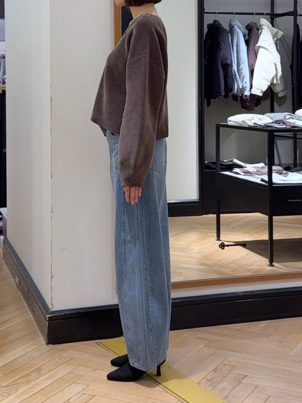 ブルー系のデニムパンツ、ブラウン系のニット/セーター、ブラック系のブーツを着用したレディースの秋コーディネートの2枚目の写真