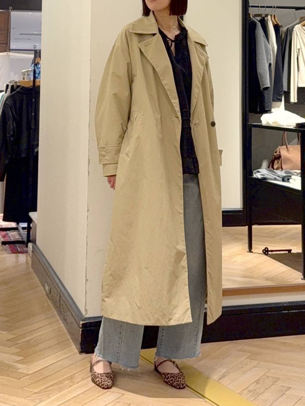 ブルー系のデニムパンツ、ブラウン系のショルダーバッグ、ベージュ系のその他アウターを着用したレディースの春コーディネートの2枚目の写真