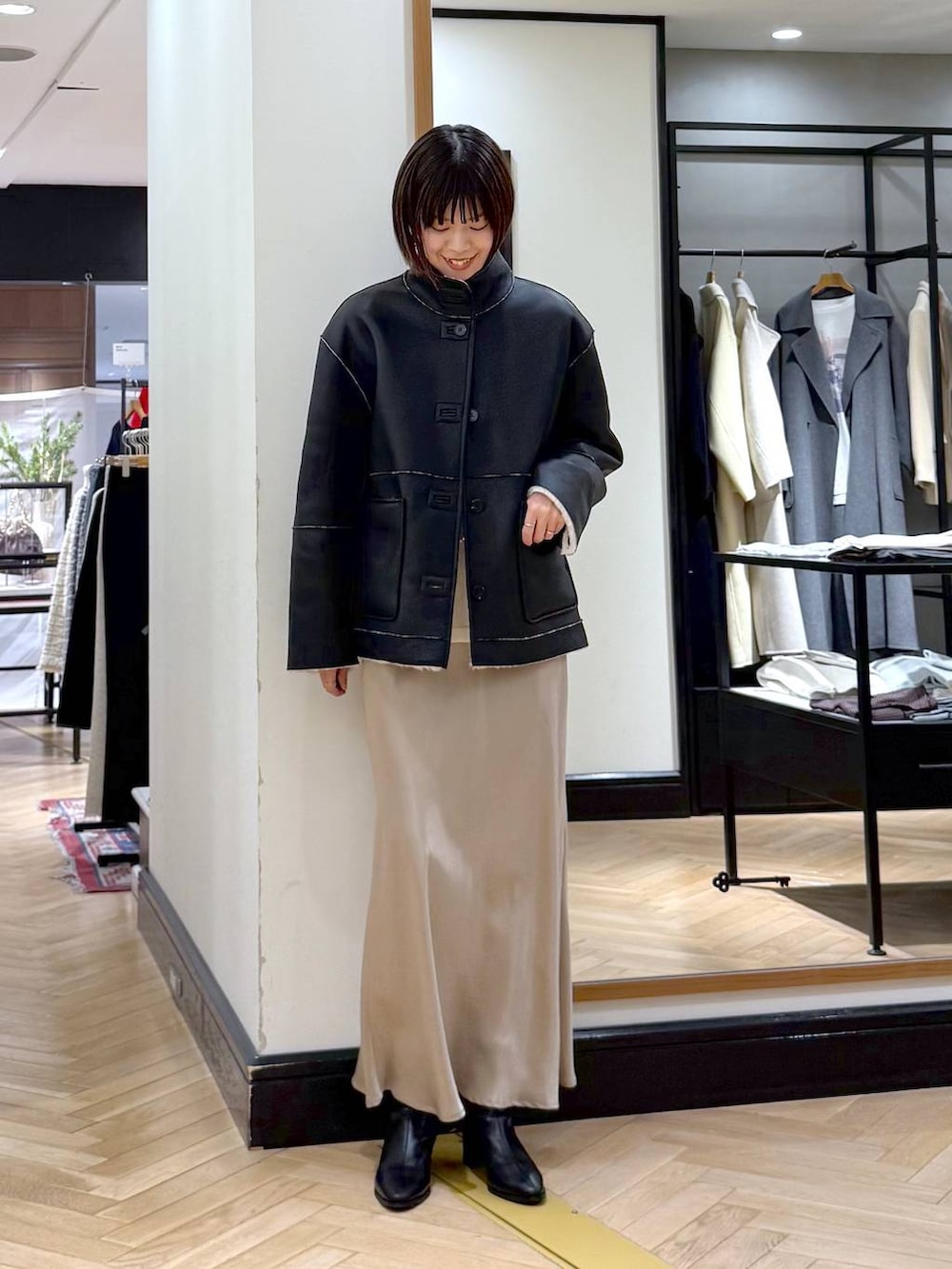 ブラック系のブーツ、ベージュ系のスカート、ブラック系のその他アウターを着用したレディースの冬コーディネートの3枚目の写真