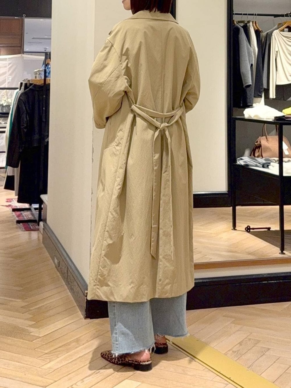 ブルー系のデニムパンツ、ブラウン系のショルダーバッグ、ベージュ系のその他アウターを着用したレディースの春コーディネートの4枚目の写真