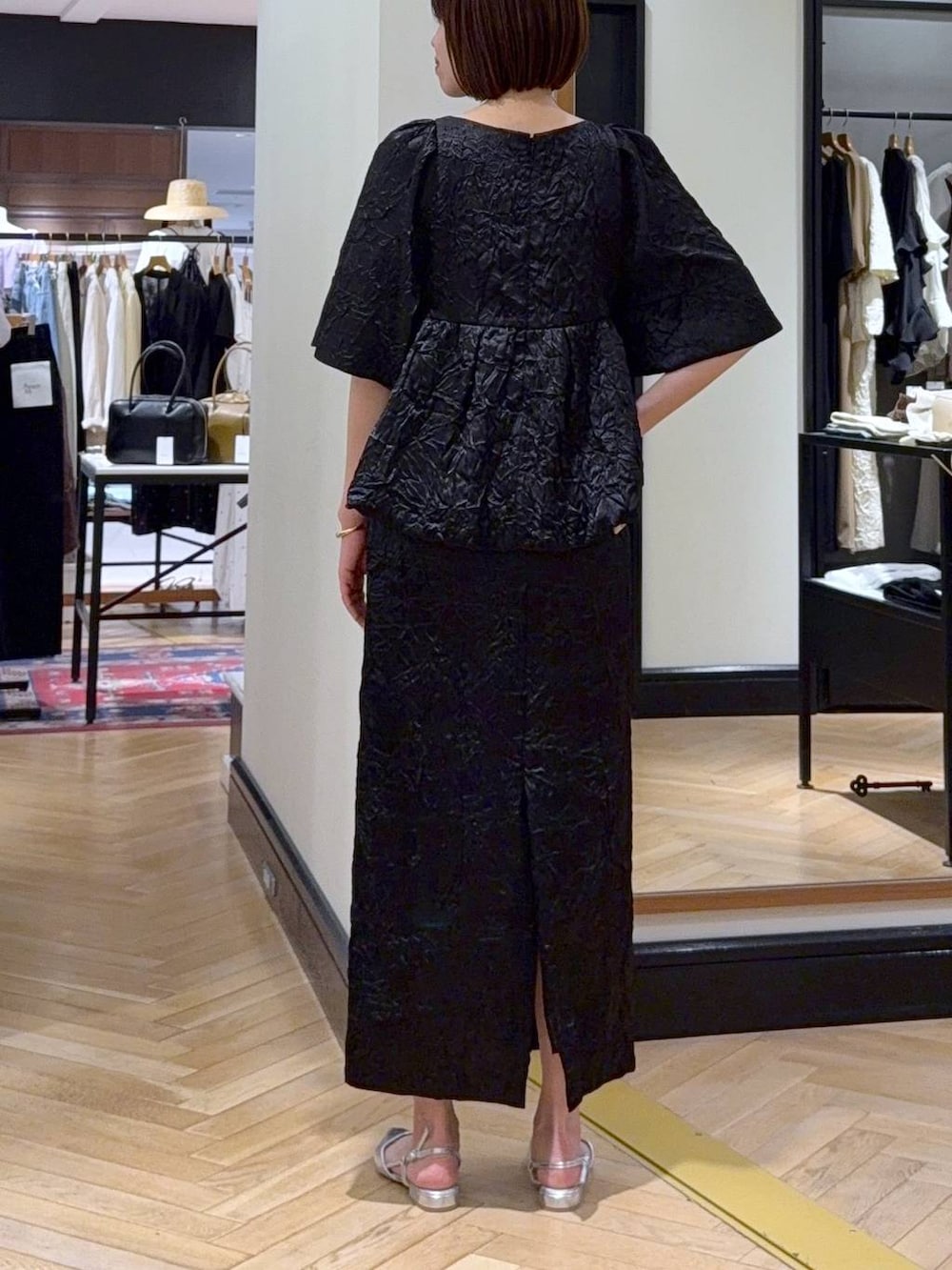 ホワイト系のハンドバッグ、シルバー系のパンプス、ブラック系のワンピースを着用したレディースの夏コーディネートの4枚目の写真