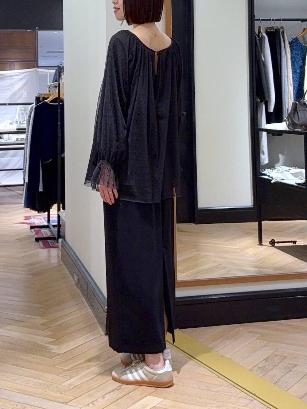 グリーン系のトートバッグ、ベージュ系のスニーカー、ブラック系のシャツ/ブラウスを着用したレディースの春コーディネートの3枚目の写真