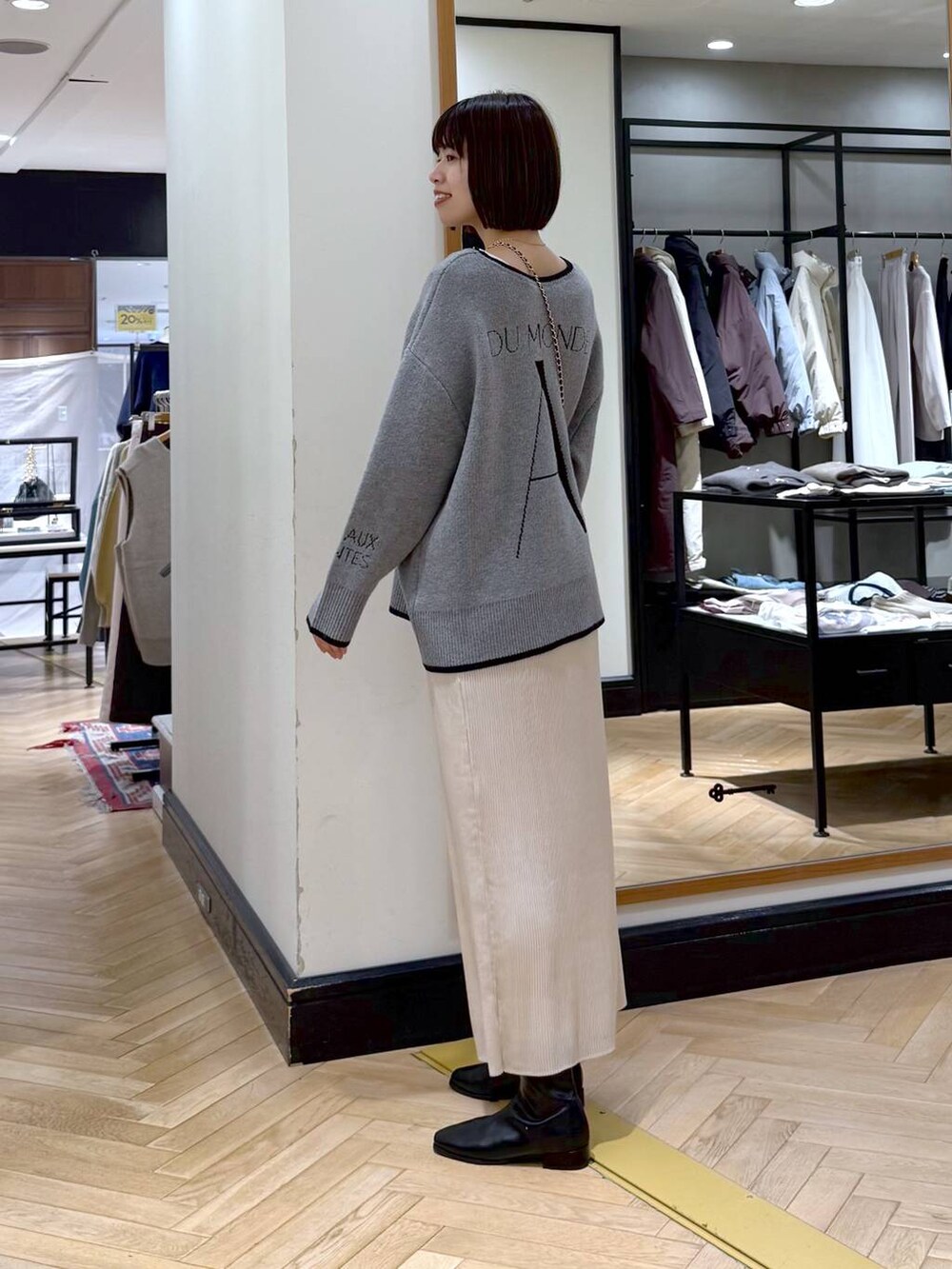 ブラック系のブーツ、ホワイト系のスカート、グレー系のニット/セーターを着用したレディースの秋コーディネートの3枚目の写真