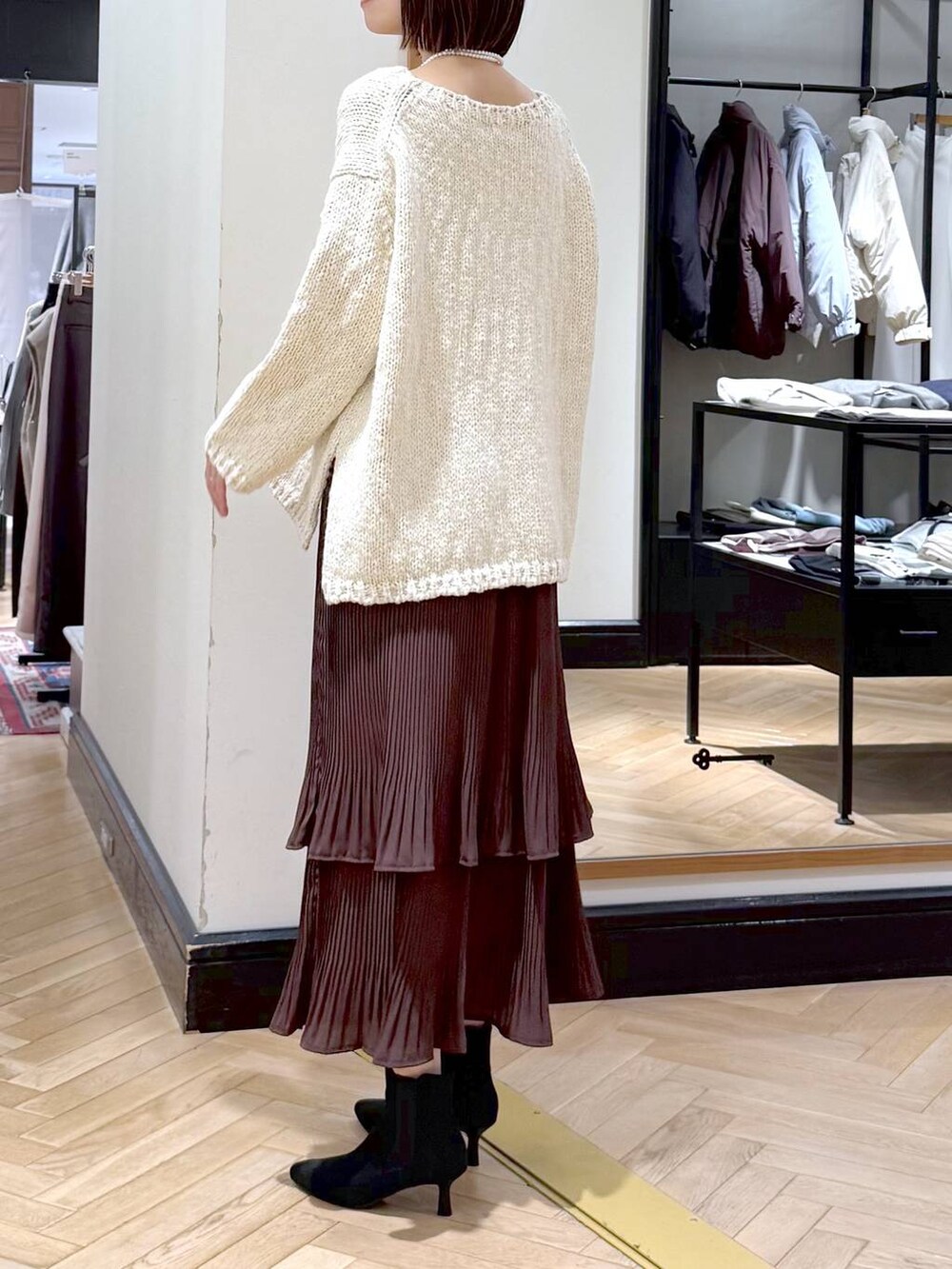 ブラウン系のスカート、ブラック系のショルダーバッグ、ブラック系のブーツを着用したレディースの秋コーディネートの3枚目の写真