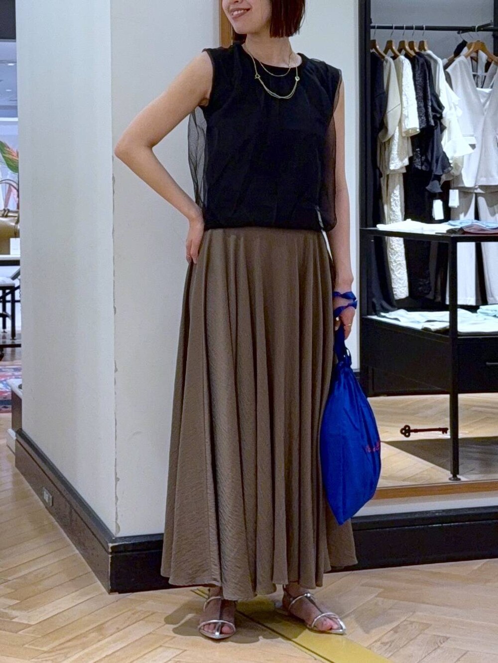 シルバー系のサンダル、ブラック系のニット/セーター、グリーン系のスカートを着用したレディースの夏コーディネートの6枚目の写真