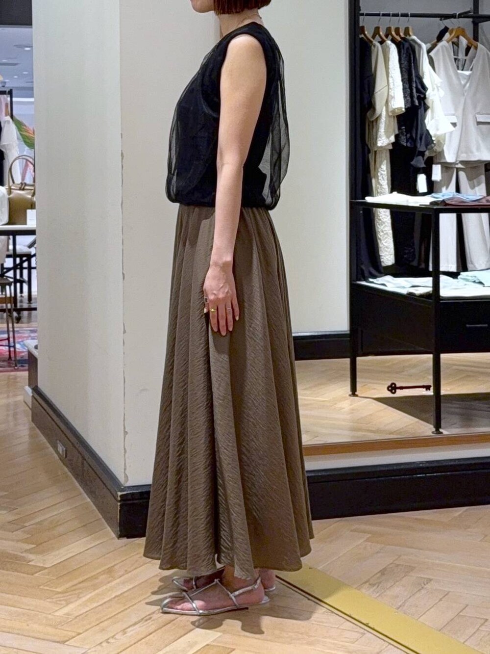 シルバー系のサンダル、ブラック系のニット/セーター、グリーン系のスカートを着用したレディースの夏コーディネートの2枚目の写真