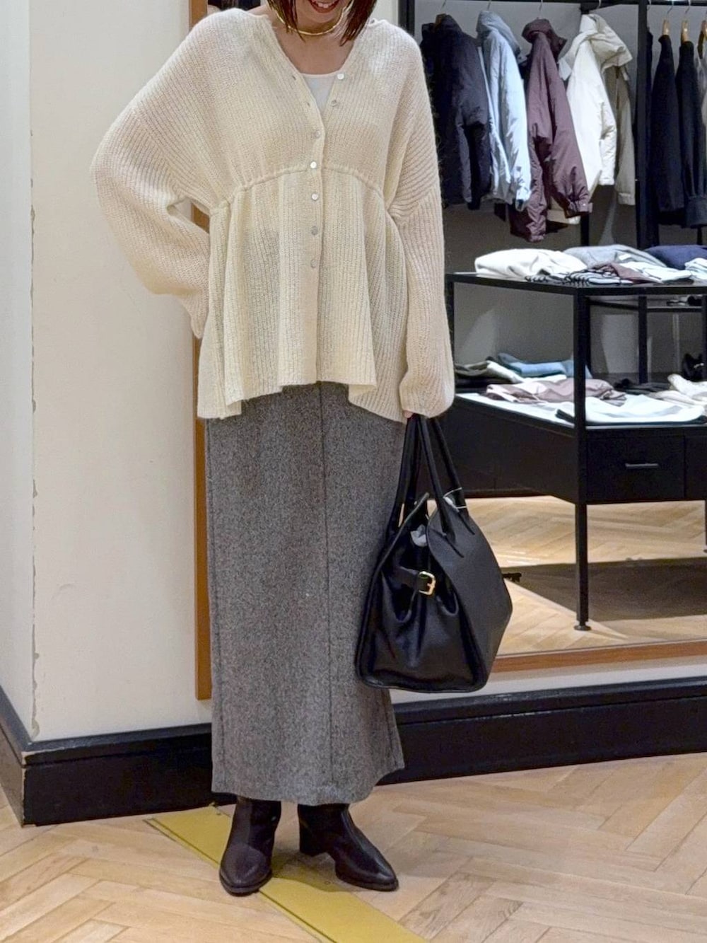ブラウン系のブーツ、ブラック系のショルダーバッグ、ブラック系のスカートを着用したレディースの秋コーディネートの2枚目の写真
