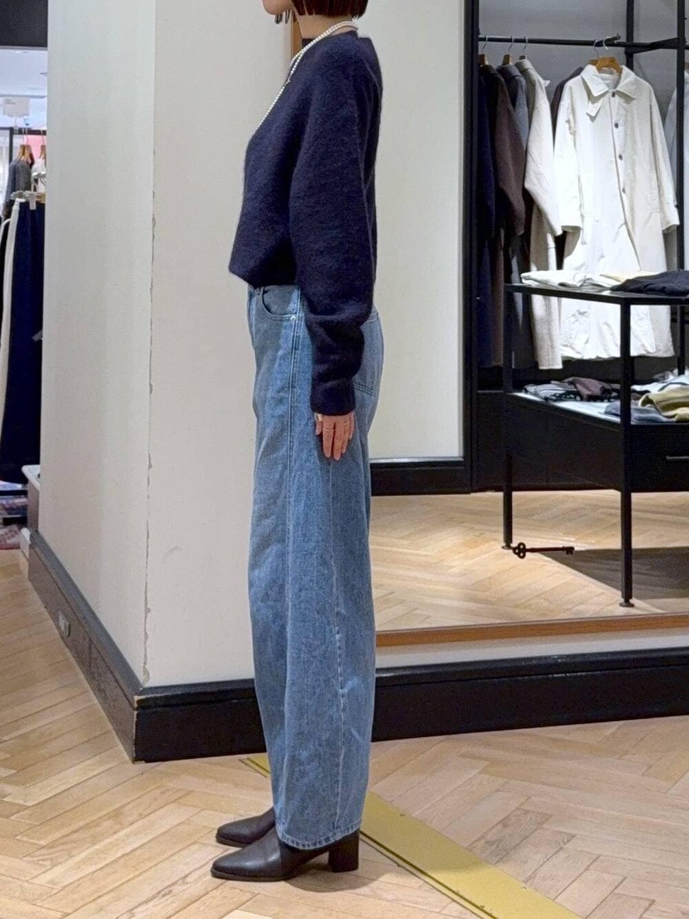 ブルー系のニット/セーター、ブルー系のデニムパンツ、ブラウン系のブーツを着用したレディースの秋コーディネートの2枚目の写真