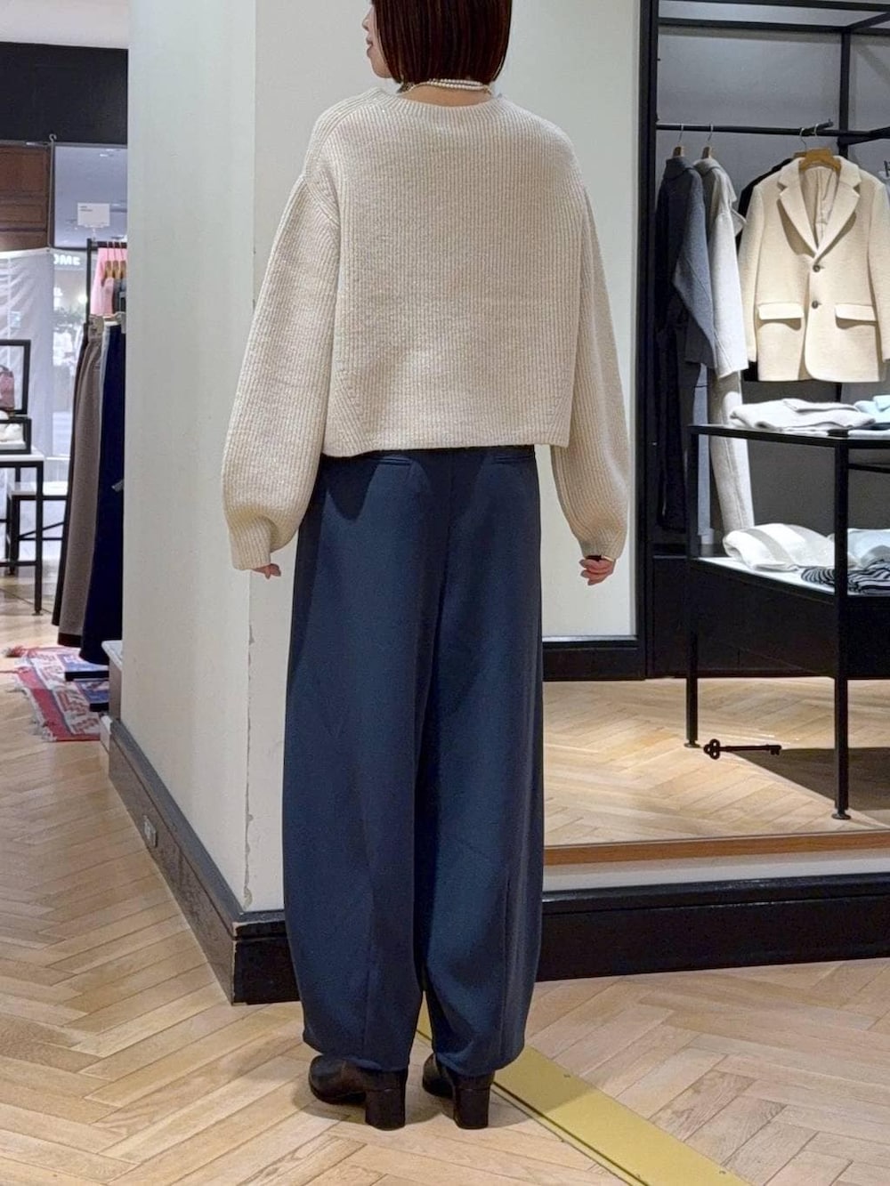 ブラック系のブーツ、ホワイト系のニット/セーター、ブラウン系のハンドバッグを着用したレディースの冬コーディネートの4枚目の写真