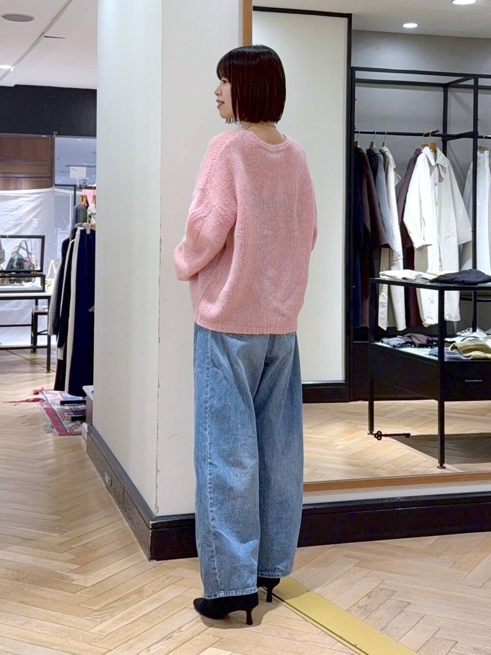 ブルー系のデニムパンツ、ブラック系のショルダーバッグ、ブラック系のブーツを着用したレディースの秋コーディネートの3枚目の写真