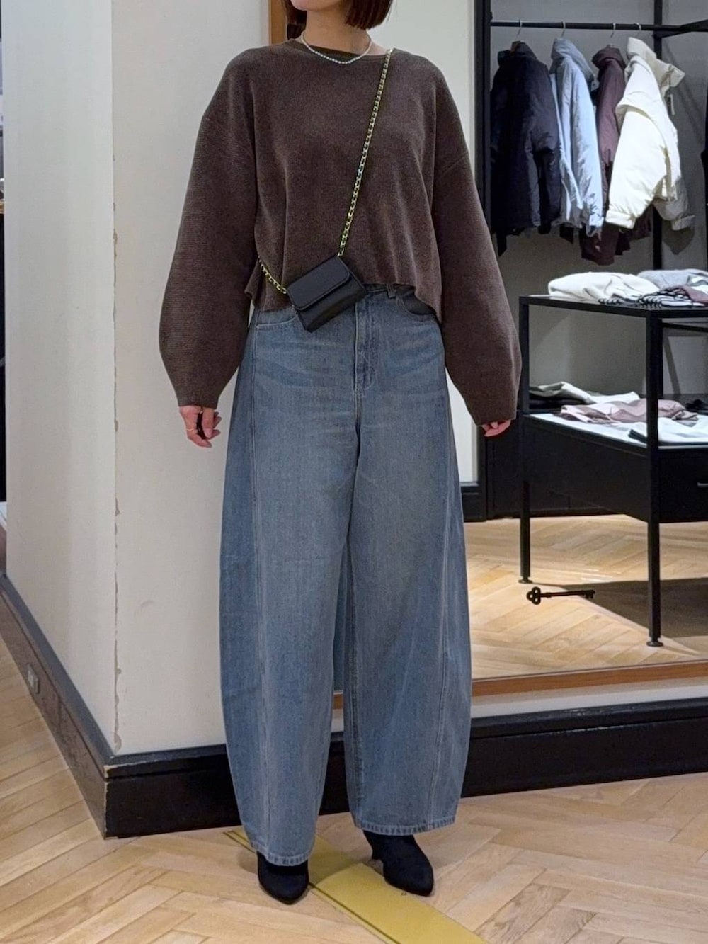 ブルー系のデニムパンツ、ブラウン系のニット/セーター、ブラック系のブーツを着用したレディースの秋コーディネートの4枚目の写真