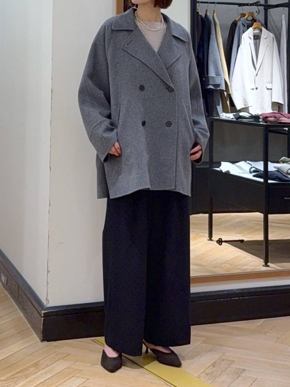 グレー系のその他アウター、ホワイト系のニット/セーター、ブラック系のスラックスを着用したレディースの秋コーディネートの3枚目の写真