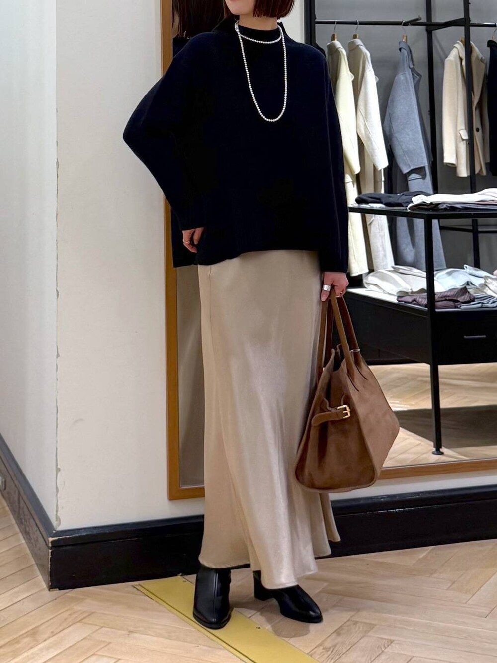 ブラック系のブーツ、ブルー系のニット/セーター、ベージュ系のスカートを着用したレディースの冬コーディネートの6枚目の写真