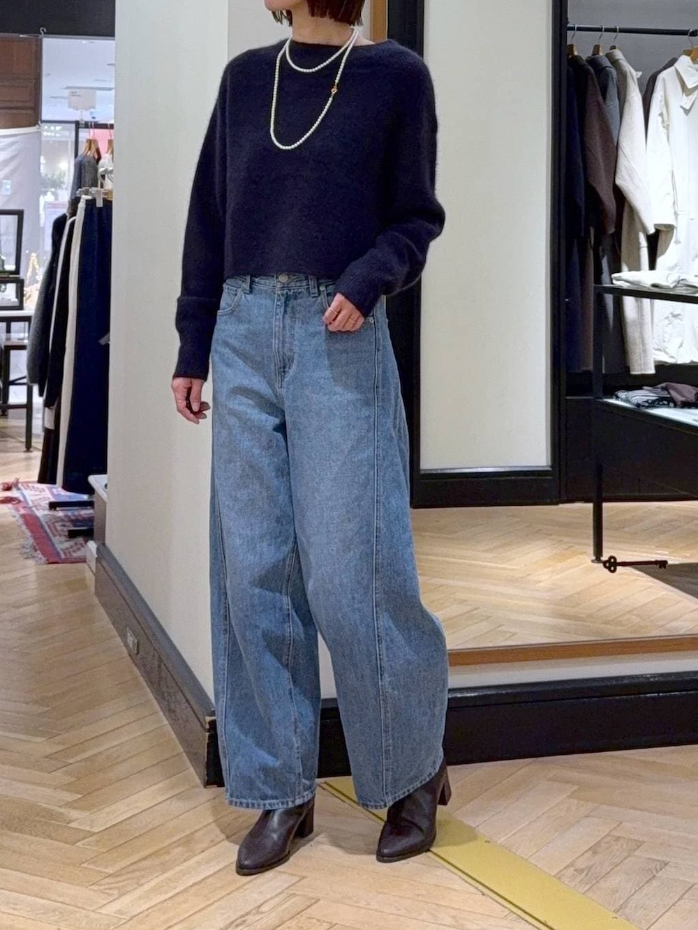 ブルー系のニット/セーター、ブルー系のデニムパンツ、ブラウン系のブーツを着用したレディースの秋コーディネートの5枚目の写真