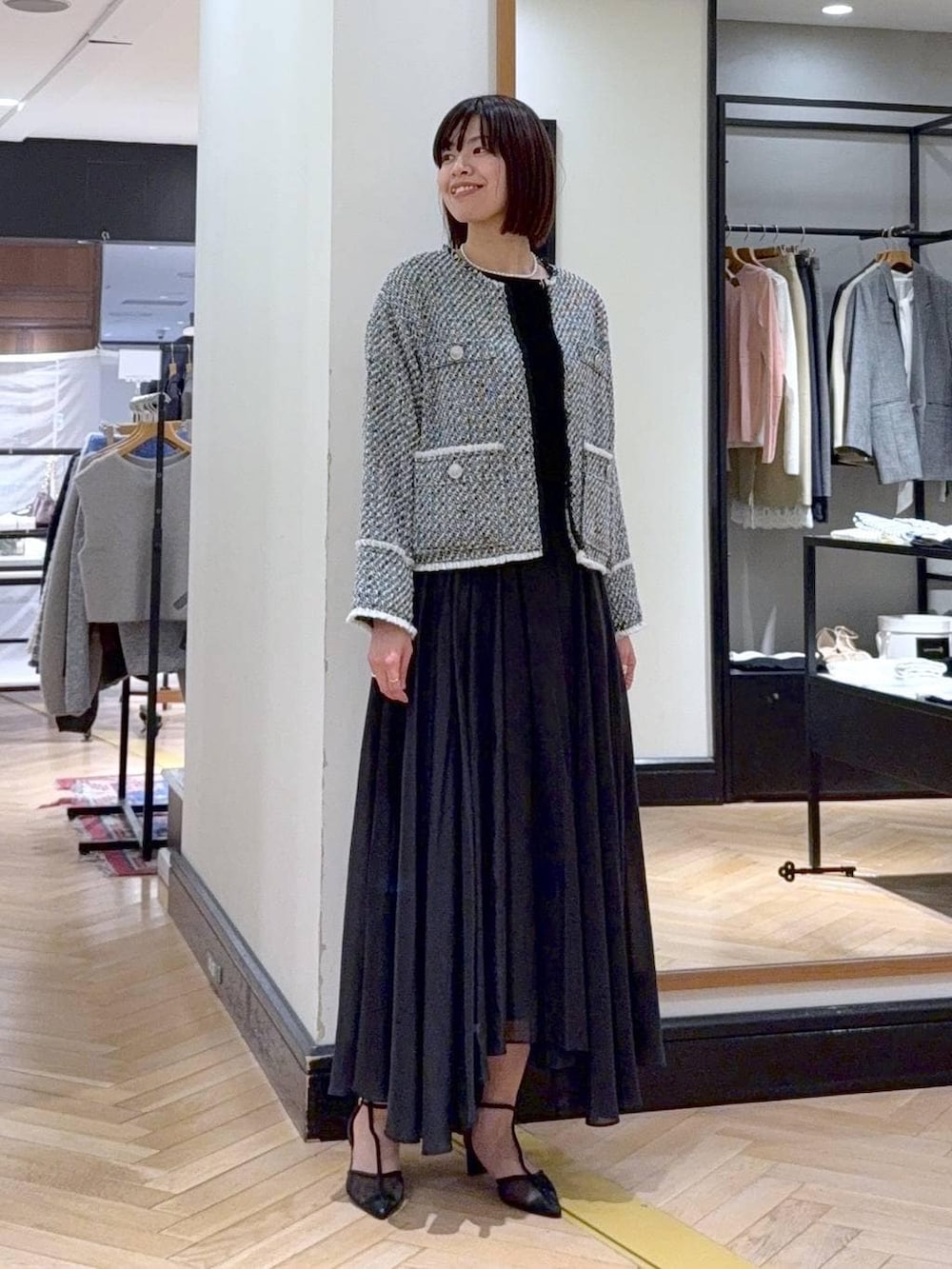 ブラック系のスカート、ブラック系のノーカラージャケット、ブラック系のパンプスを着用したレディースの冬コーディネートの2枚目の写真