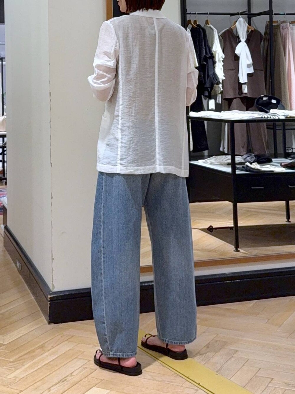 ブルー系のデニムパンツ、ホワイト系のテーラードジャケット、ブラック系のハンドバッグを着用したレディースの夏コーディネートの3枚目の写真