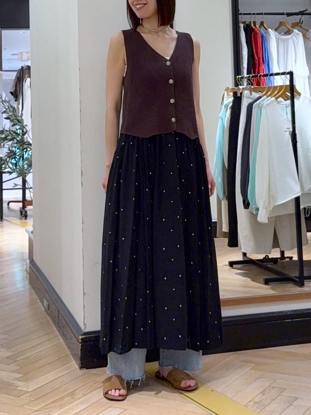 ブラック系のワンピース、ブルー系のデニムパンツ、ブラウン系のベストを着用したレディースの春コーディネートの2枚目の写真